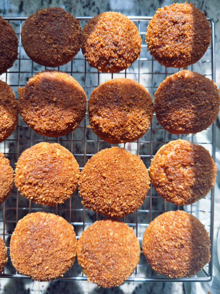 Freshly baked mini apple muffins cooling on a wire rack, showcasing their golden-brown, cinnamon-sugar-coated tops.