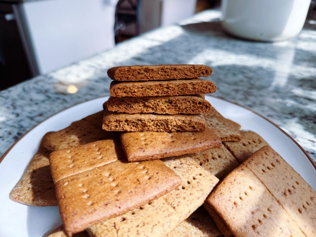 A plate of assorted cookies, including stacked gingerbread cookies and flat cookies, on a granite countertop.